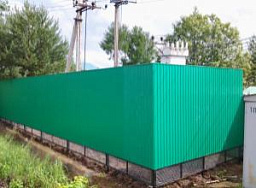 Зеленый металлический забор из профлиста с металлическими столбами и сеткой