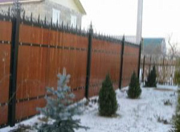 Деревянный забор для частного дома с ковкой на железных столбах